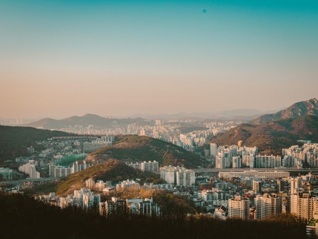 A stunning aerial view of Seoul's skyline with mountains and buildings under a clear sky.